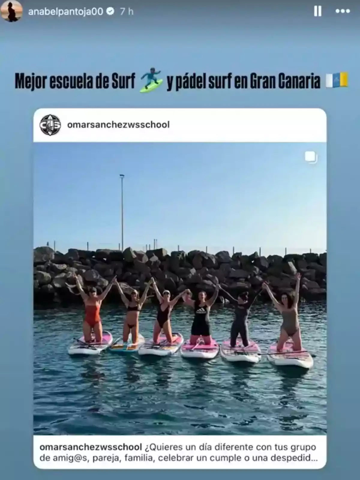 Grupo de seis personas de pie sobre tablas de paddle surf en el mar, levantando los brazos y sonriendo, con un fondo de rocas y cielo despejado. Grupo de seis personas de pie sobre tablas de paddle surf en el mar, levantando los brazos y sonriendo, con un fondo de rocas y cielo despejado.