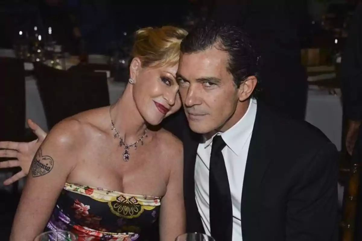 Dos personas posando juntas en un evento formal, una mujer con vestido floral y un hombre con traje negro. Dos personas posando juntas en un evento formal, una mujer con vestido floral y un hombre con traje negro.