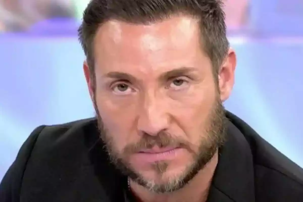 Antonio David Flores con barba y cabello corto mira fijamente a la cámara en un entorno de estudio en Sálvame. Antonio David Flores con barba y cabello corto mira fijamente a la cámara en un entorno de estudio en Sálvame.