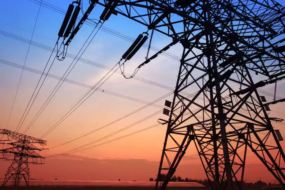 Torres de alta tensión con cables eléctricos al atardecer.
