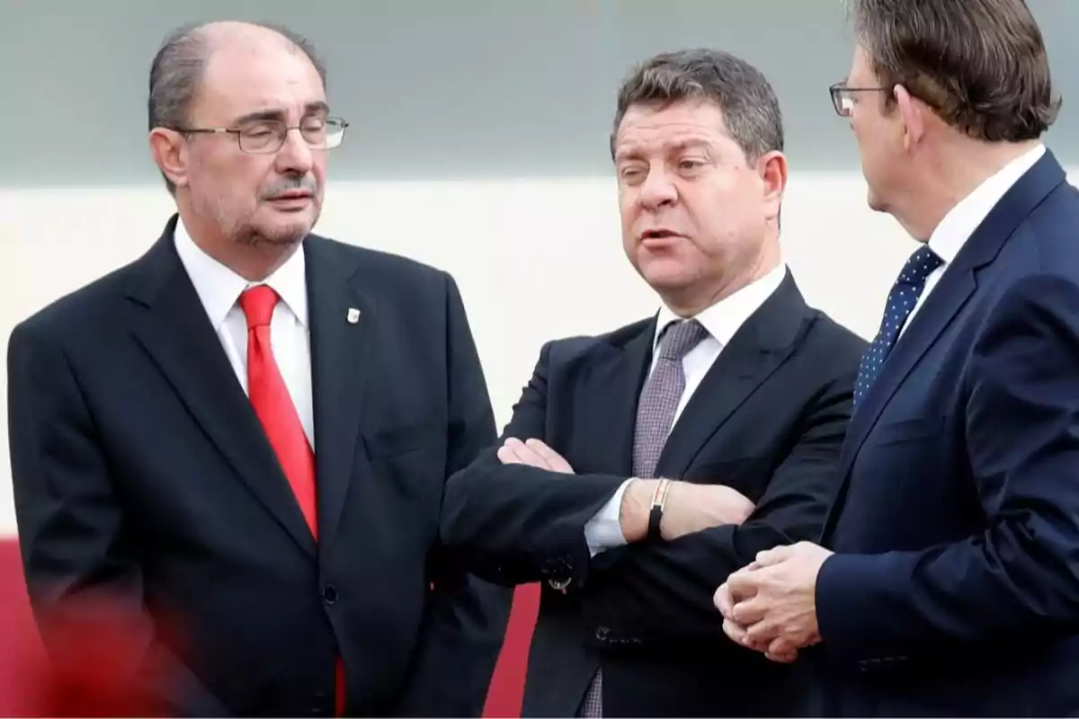 Tres hombres de traje conversando entre ellos. Tres hombres de traje conversando entre ellos.