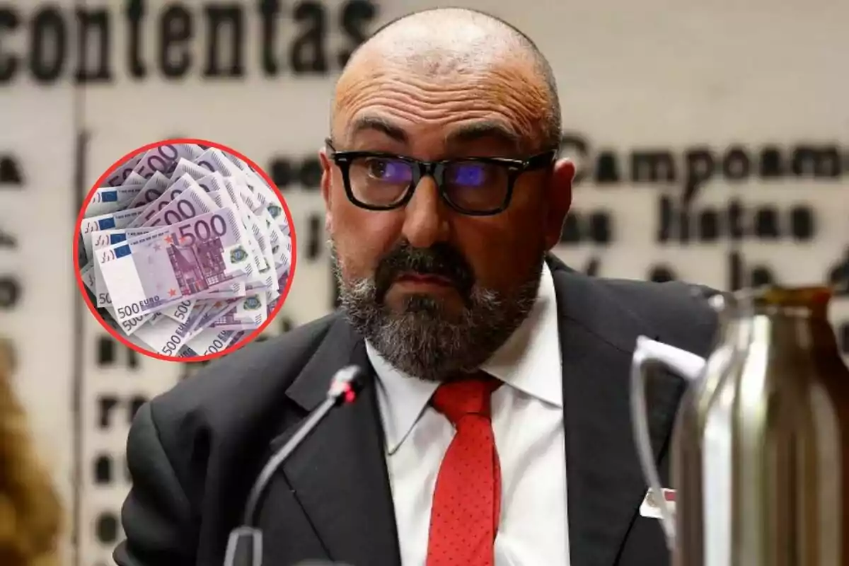 Hombre con gafas y barba en traje oscuro y corbata roja hablando en un micrófono con un círculo que muestra billetes de 500 euros en la esquina.