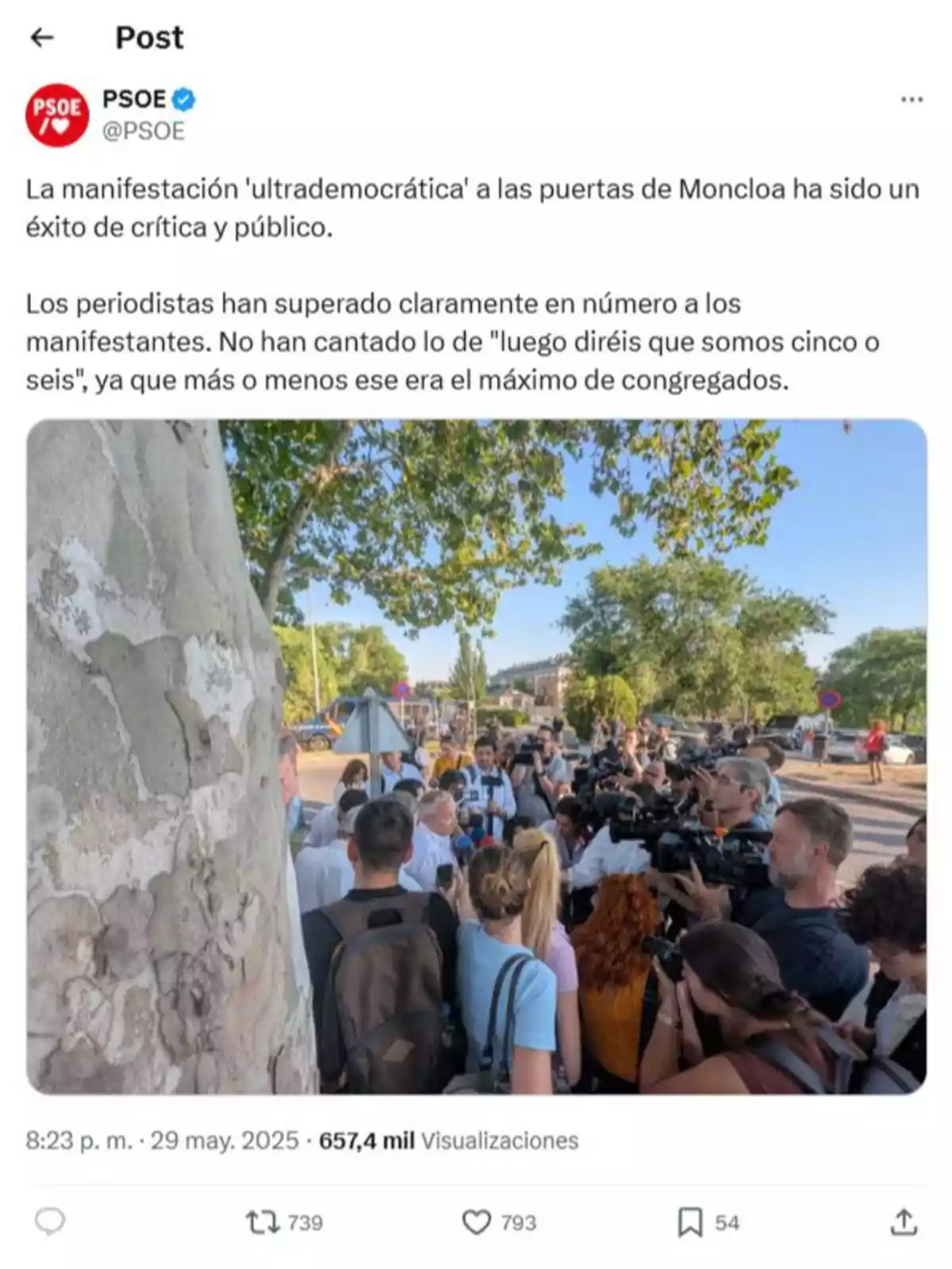 Un grupo pequeño de personas y numerosos periodistas con cámaras se reúnen al aire libre junto a un árbol y una calle, en un evento cubierto por medios de comunicación. Un grupo pequeño de personas y numerosos periodistas con cámaras se reúnen al aire libre junto a un árbol y una calle, en un evento cubierto por medios de comunicación.