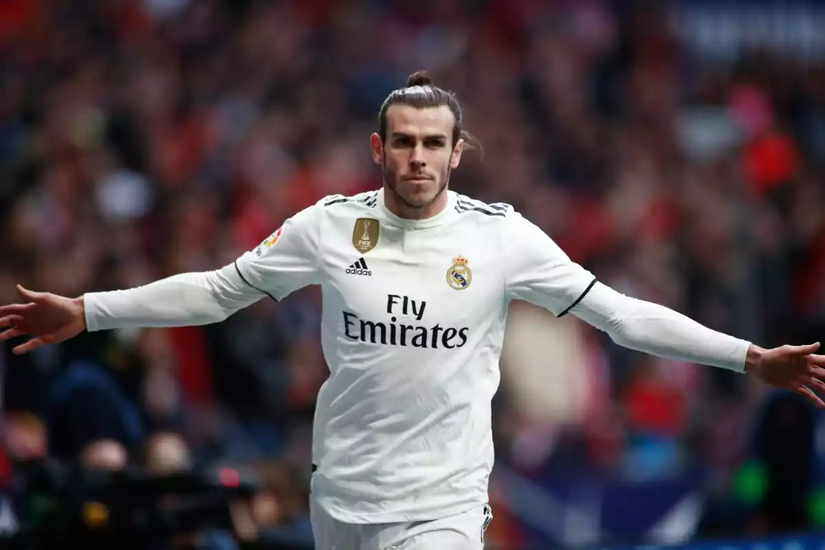 Jugador de fútbol con uniforme blanco celebrando en el campo.