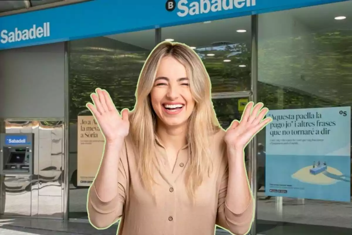 Una mujer sonriente con las manos levantadas frente a una sucursal del banco Sabadell.