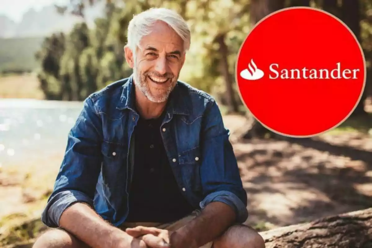 Hombre de cabello canoso y barba, sonriendo, sentado al aire libre con un logotipo de Santander en la esquina derecha.