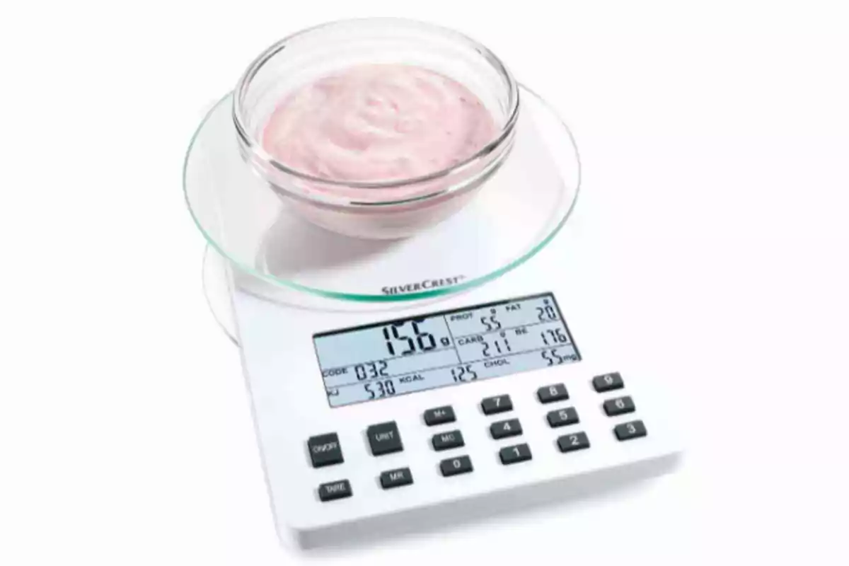Un tazón de yogur rosado sobre una báscula de cocina digital mostrando el peso y valores nutricionales. Un tazón de yogur rosado sobre una báscula de cocina digital mostrando el peso y valores nutricionales.