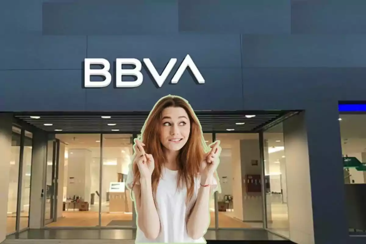 Una mujer con los dedos cruzados frente a una sucursal del banco BBVA.