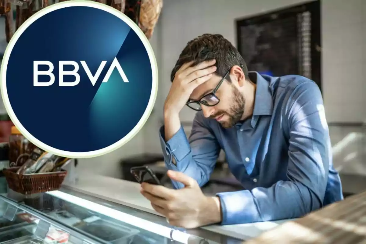 Hombre preocupado mirando su teléfono móvil con el logo de BBVA en la esquina superior izquierda.