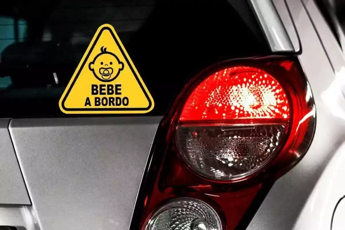 Un coche con una señal amarilla triangular que dice "BEBE A BORDO" y muestra la imagen de un bebé con chupete.