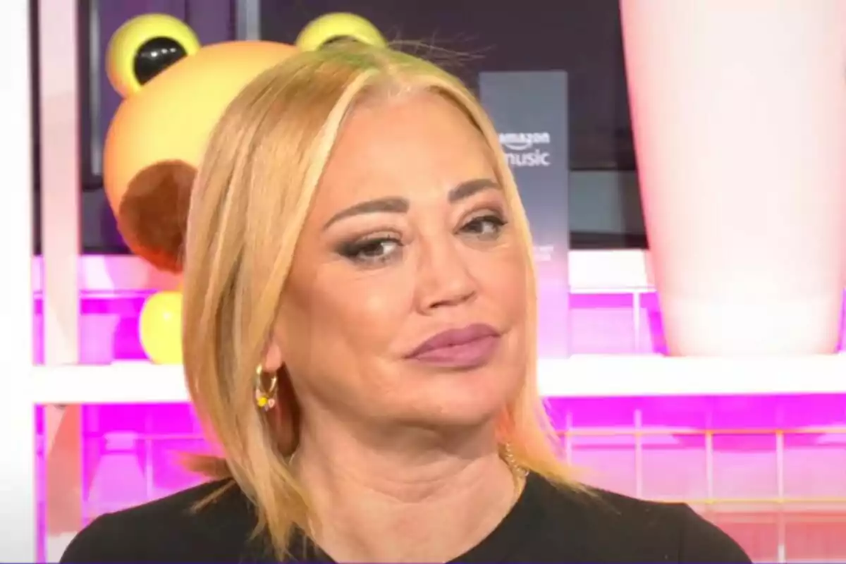Belén Esteban con cabello rubio y expresión seria en un entorno colorido en 'Ni que fuéramos shhh'. Belén Esteban con cabello rubio y expresión seria en un entorno colorido en 'Ni que fuéramos shhh'.