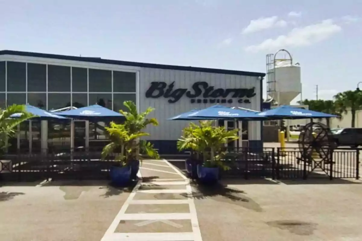 Facade of a brewery with blue umbrellas and potted plants in front of the entrance Facade of a brewery with blue umbrellas and potted plants in front of the entrance