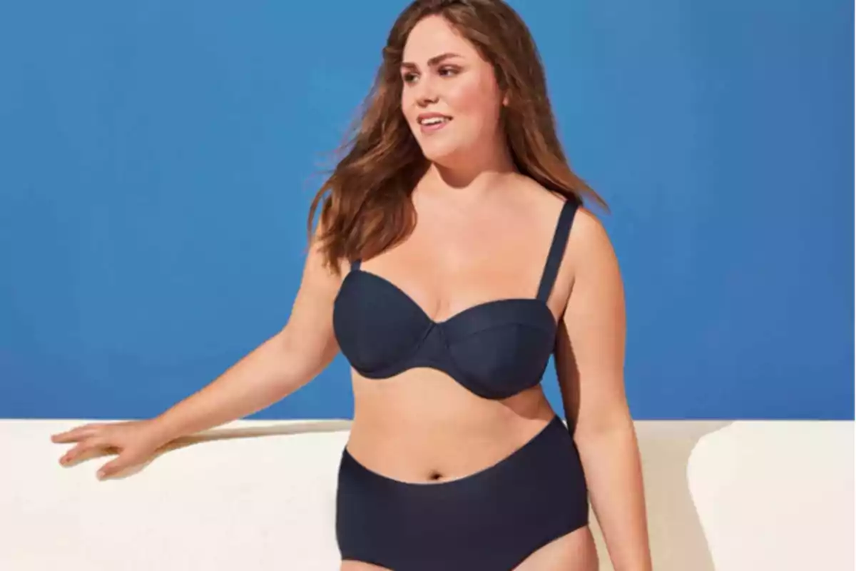Mujer con bikini negro posando frente a un fondo azul. Mujer con bikini negro posando frente a un fondo azul.