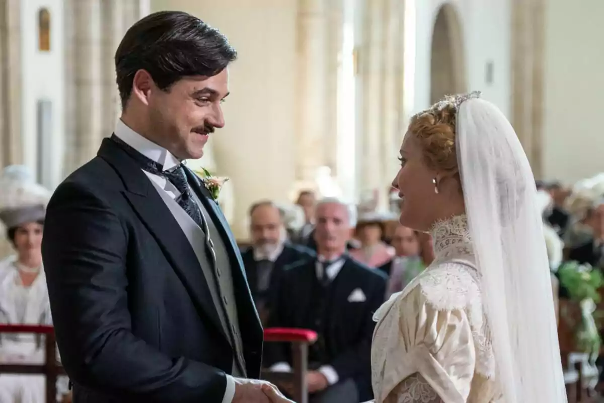 Arturo Sancho and Ana Garcés dressed as bride and groom look at each other tenderly at a wedding ceremony in La Promesa.