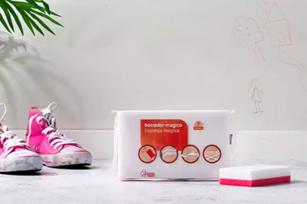 Un par de tenis rosas sucios junto a un paquete de esponjas mágicas para limpiar y una esponja fuera del paquete con dibujos hechos con crayón en la pared de fondo Un par de tenis rosas sucios junto a un paquete de esponjas mágicas para limpiar y una esponja fuera del paquete con dibujos hechos con crayón en la pared de fondo