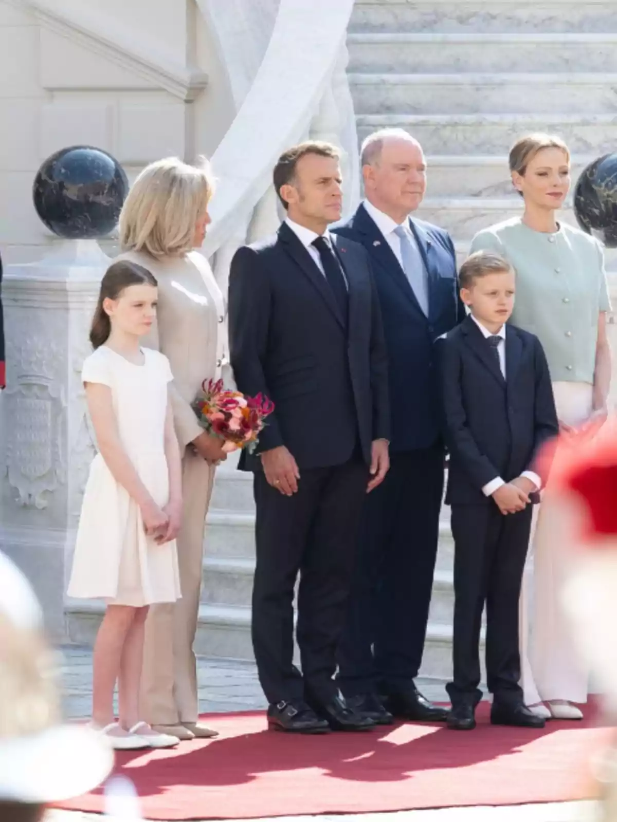 Group of six elegantly dressed people posing on a red carpet in front of a marble staircase Group of six elegantly dressed people posing on a red carpet in front of a marble staircase