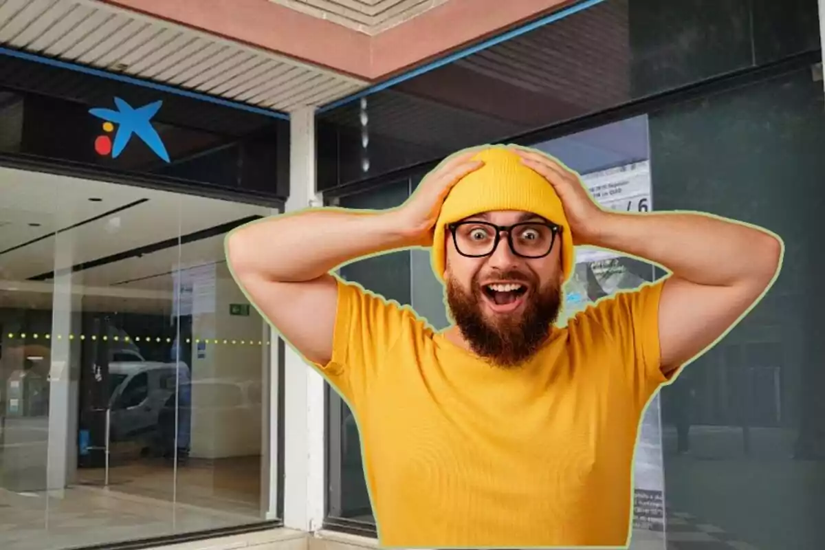 Hombre con gorro y camiseta amarillos, con expresión de sorpresa, frente a una sucursal bancaria.