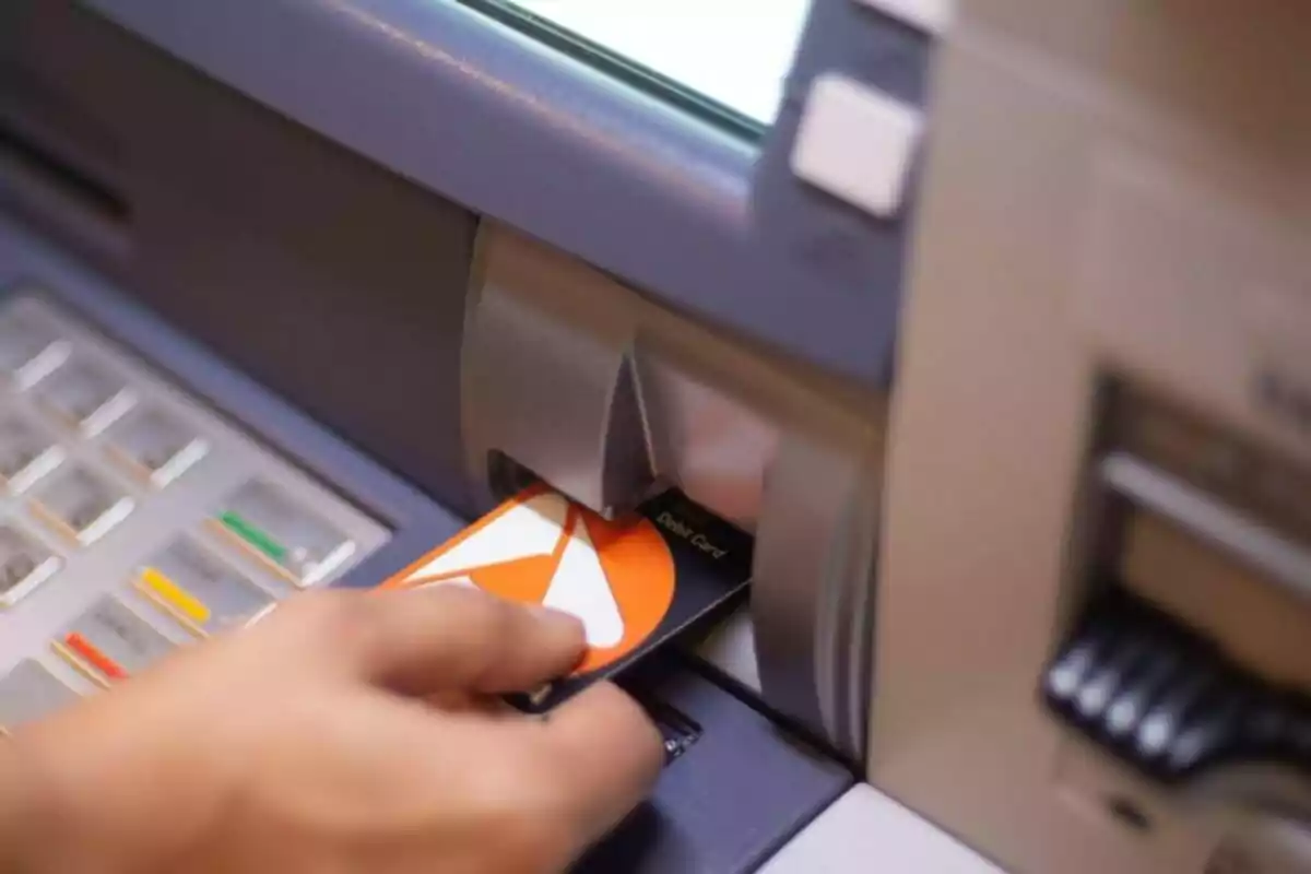 Persona insertando una tarjeta de débito en un cajero automático. Persona insertando una tarjeta de débito en un cajero automático.