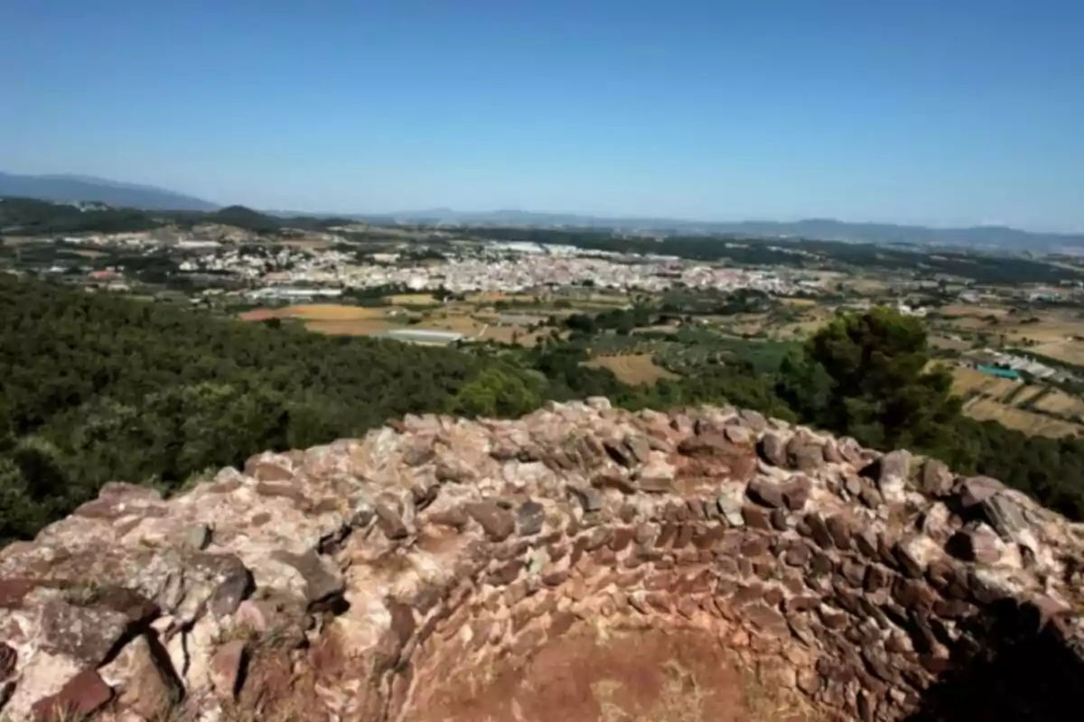 Vista panorámica de un paisaje rural con colinas, vegetación y una estructura de piedra en primer plano. Vista panorámica de un paisaje rural con colinas, vegetación y una estructura de piedra en primer plano.