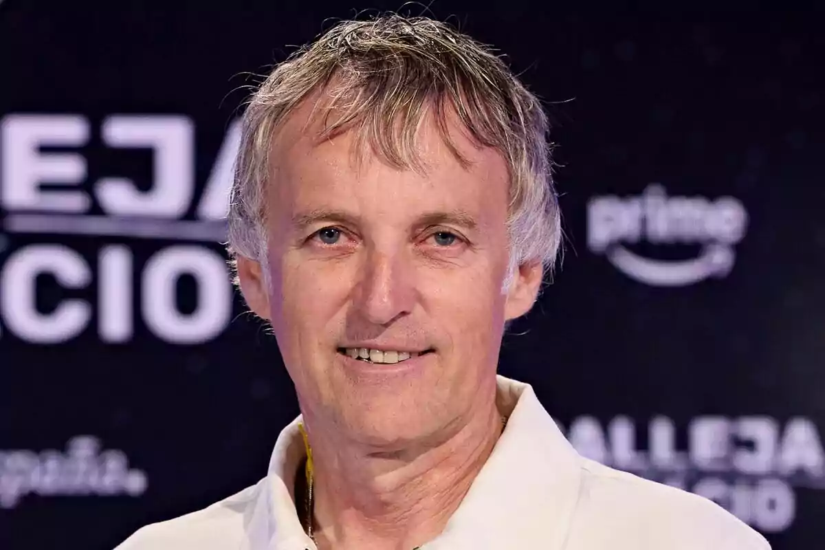Jesús Calleja de cabello canoso y camisa blanca sonríe frente a un fondo oscuro con texto borroso en Calleja en el espacio. Jesús Calleja de cabello canoso y camisa blanca sonríe frente a un fondo oscuro con texto borroso en Calleja en el espacio.