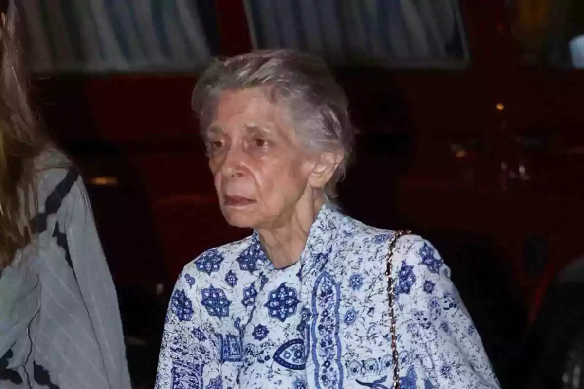 Irene of Greece with short gray hair wears a blue and white patterned blouse as she walks down the street. Irene of Greece with short gray hair wears a blue and white patterned blouse as she walks down the street.