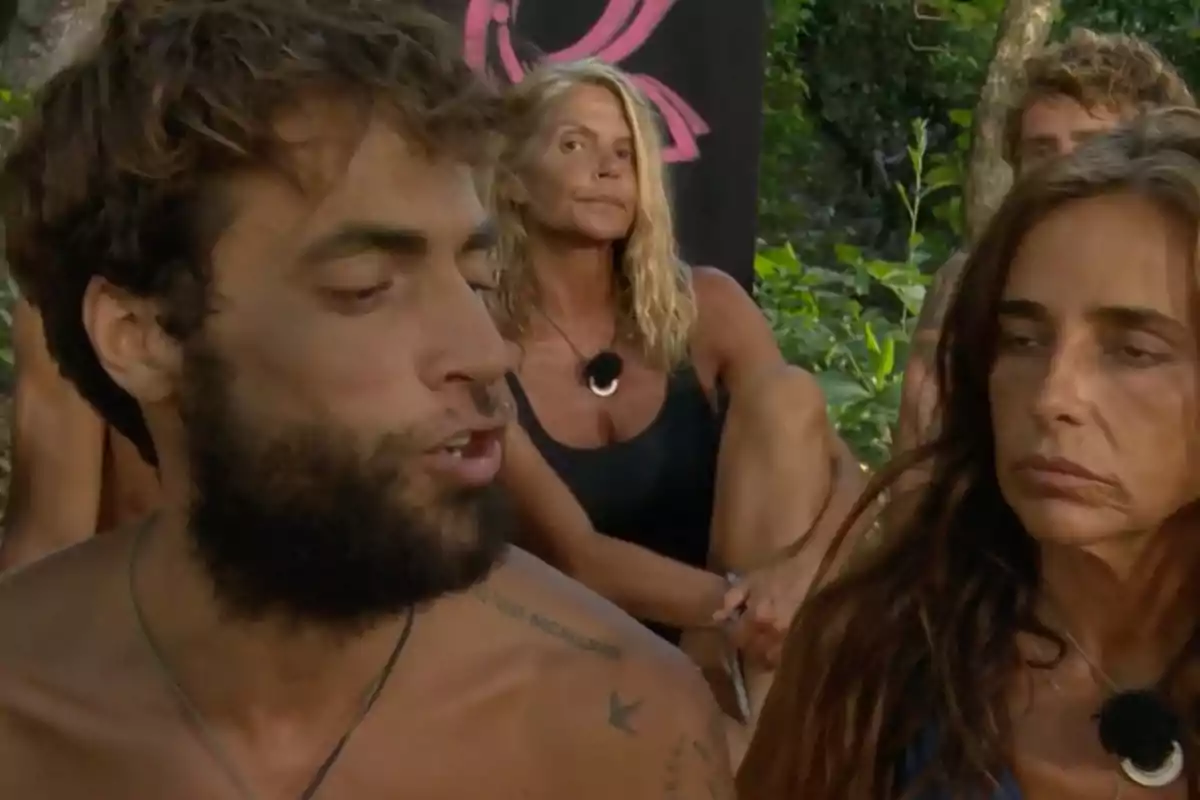 Montoya, Carmen Alcayde y Makoke con expresiones serias sentados al aire libre en un entorno selvático Montoya, Carmen Alcayde y Makoke con expresiones serias sentados al aire libre en un entorno selvático