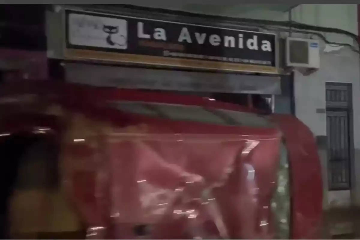 Un coche rojo volcado frente a un local llamado Un coche rojo volcado frente a un local llamado