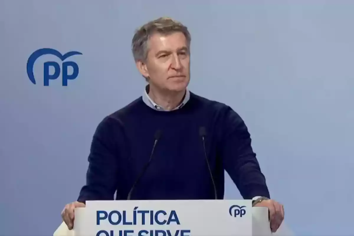 Un hombre de pie detrás de un podio con el logotipo del PP y el texto "Política que sirve".