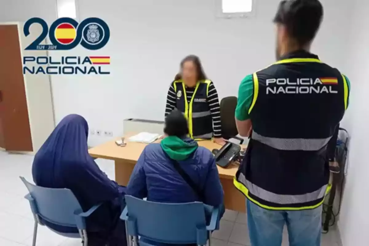 En una oficina, dos personas sentadas frente a un escritorio son atendidas por personal de la Policía Nacional, con el logotipo de la institución visible en la pared. En una oficina, dos personas sentadas frente a un escritorio son atendidas por personal de la Policía Nacional, con el logotipo de la institución visible en la pared.
