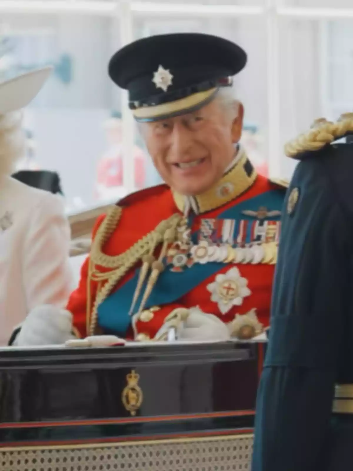 Hombre mayor con uniforme militar rojo y gorra negra sonríe mientras está sentado en un carruaje elegante Hombre mayor con uniforme militar rojo y gorra negra sonríe mientras está sentado en un carruaje elegante
