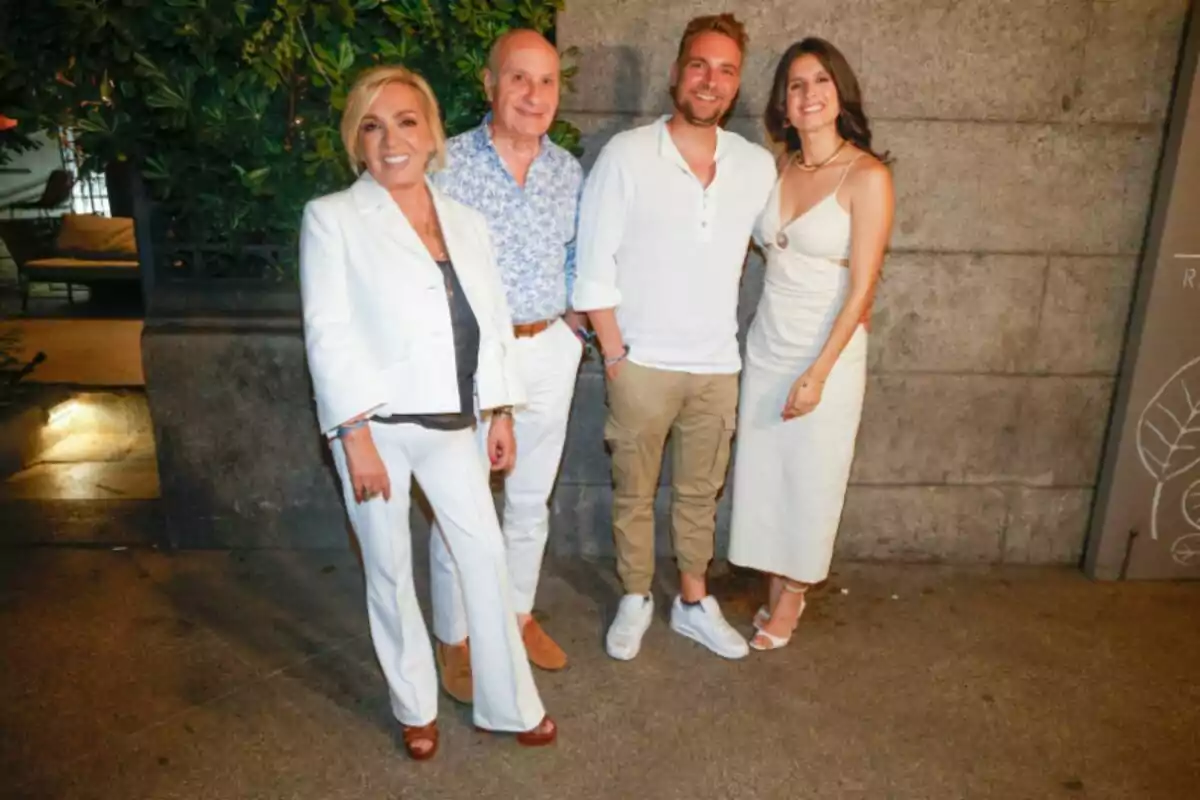Carmen Borrego, José Carlos Bernal, José María Almoguera y María Sánchez posan sonrientes frente a una pared de piedra, dos mujeres y dos hombres, todos vestidos con ropa clara y elegante en un ambiente nocturno al aire libre. Carmen Borrego, José Carlos Bernal, José María Almoguera y María Sánchez posan sonrientes frente a una pared de piedra, dos mujeres y dos hombres, todos vestidos con ropa clara y elegante en un ambiente nocturno al aire libre.