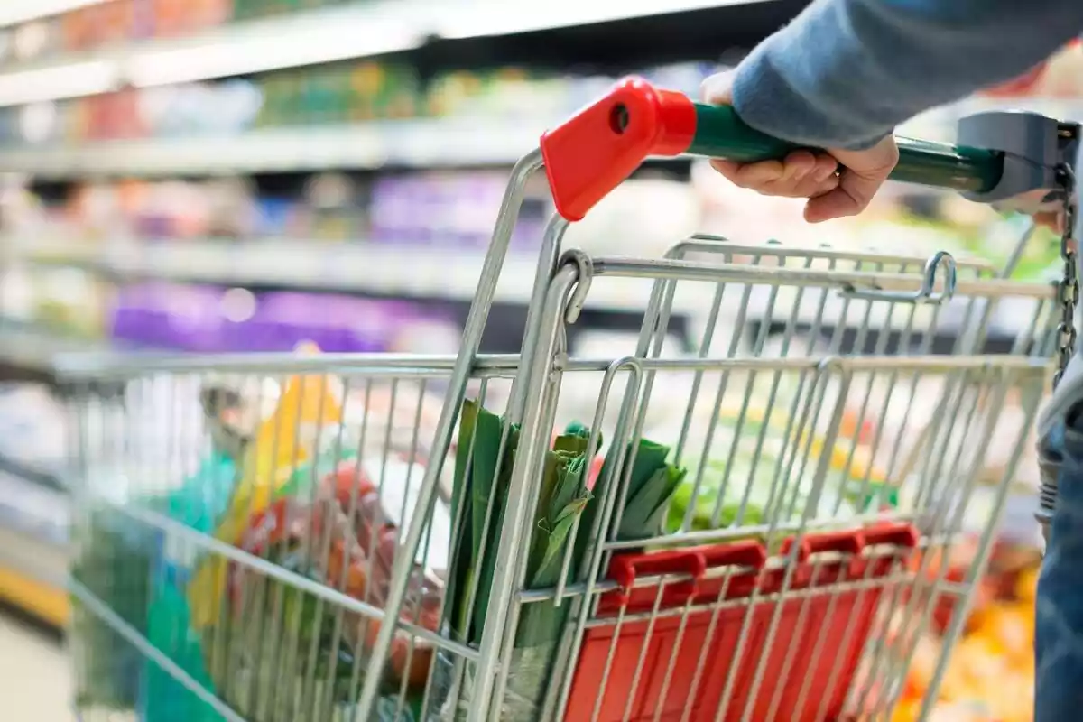 Carrito de la compra lleno de productos en un pasillo del interior de un supermercado