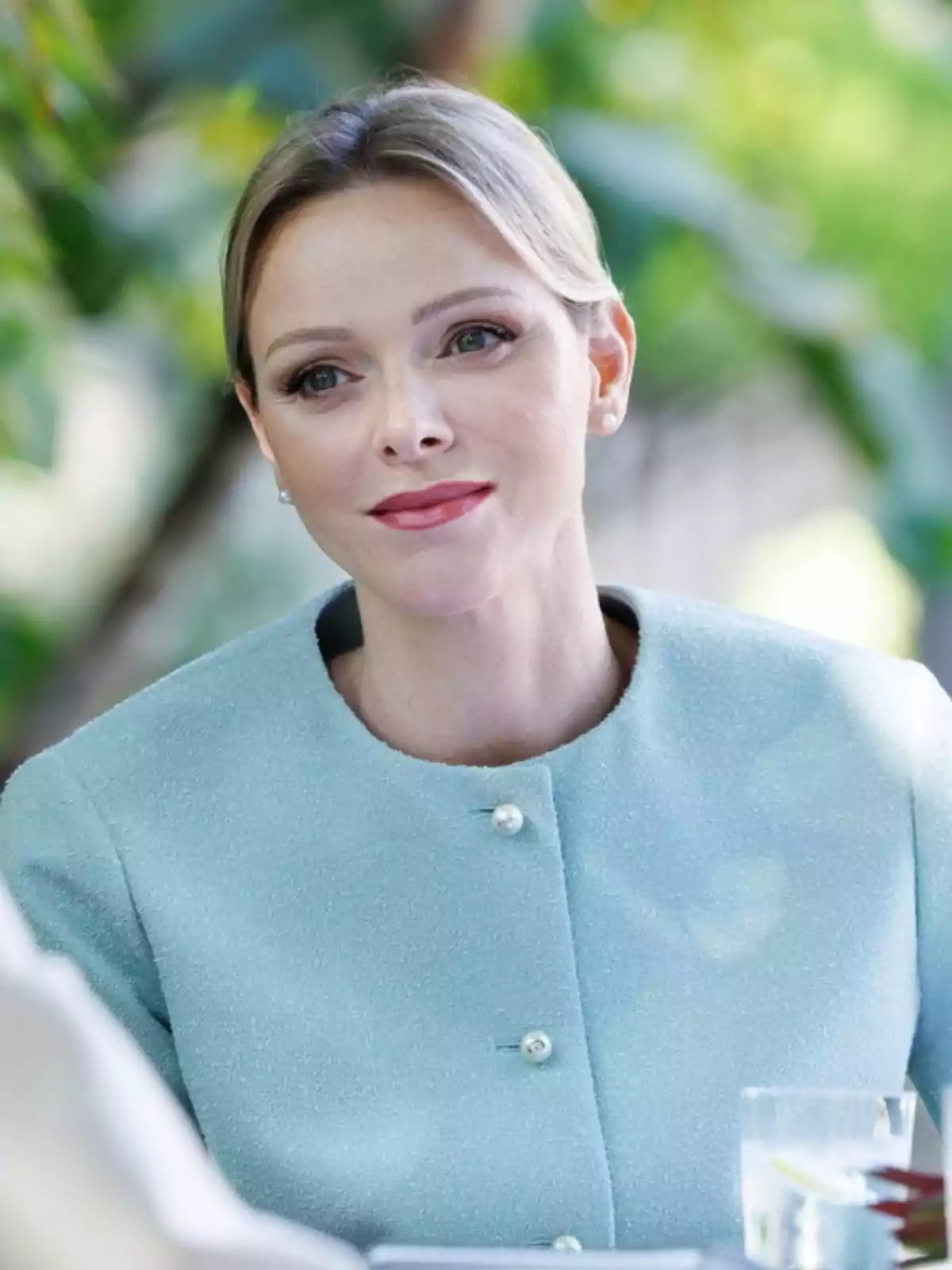 Blonde woman with her hair up and a light blue jacket sitting outdoors Blonde woman with her hair up and a light blue jacket sitting outdoors