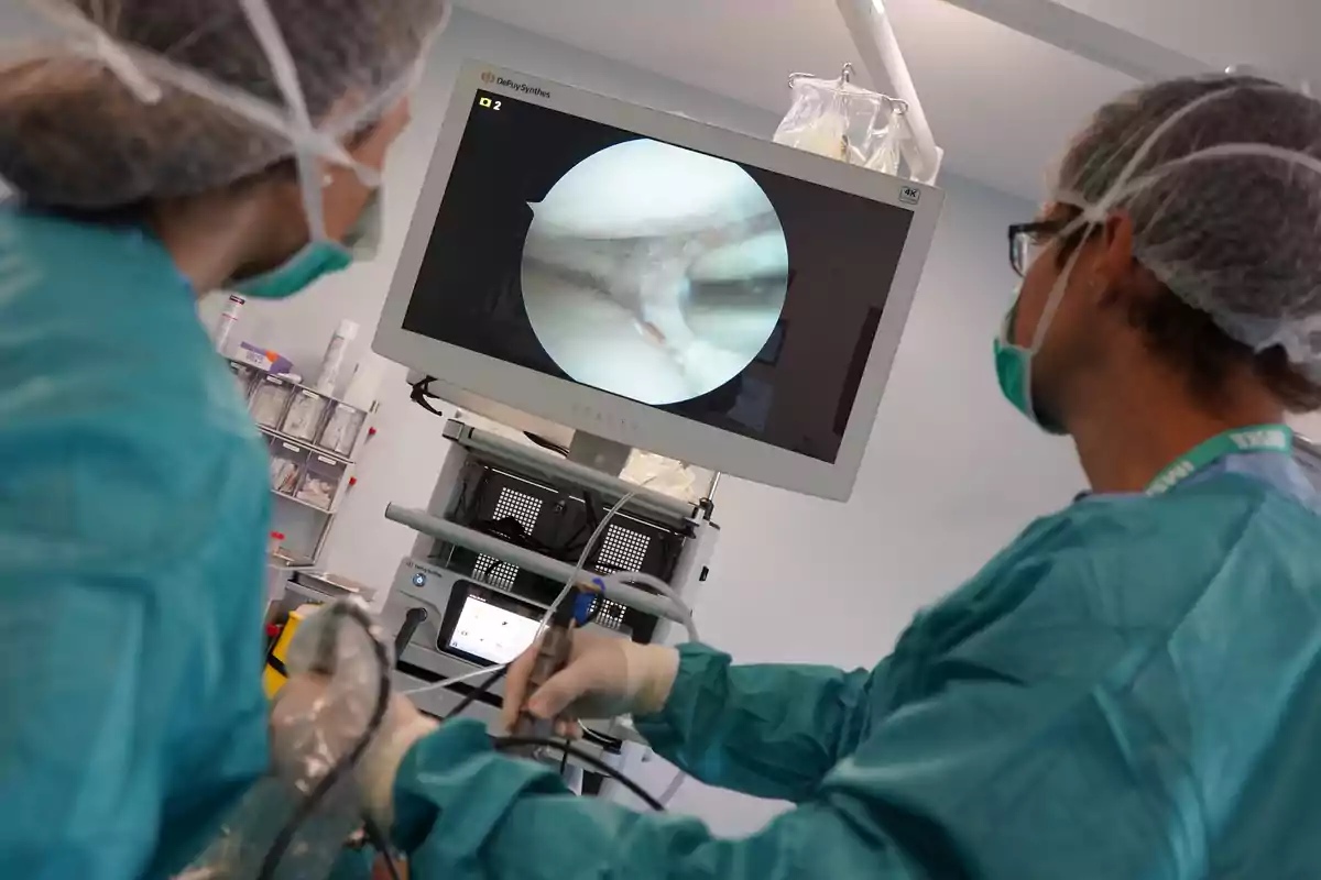 Two healthcare professionals observe a screen during a medical procedure in a clinical setting.