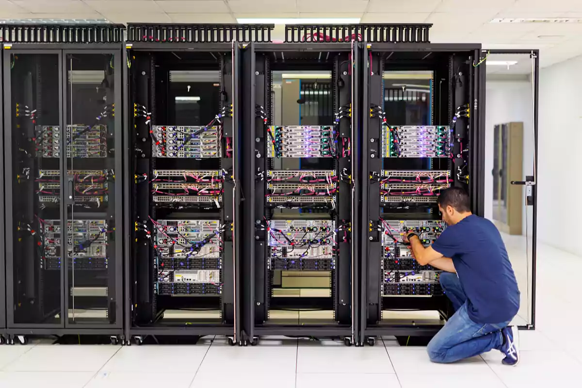 A technician inspects and adjusts cables in a data center with multiple server racks.