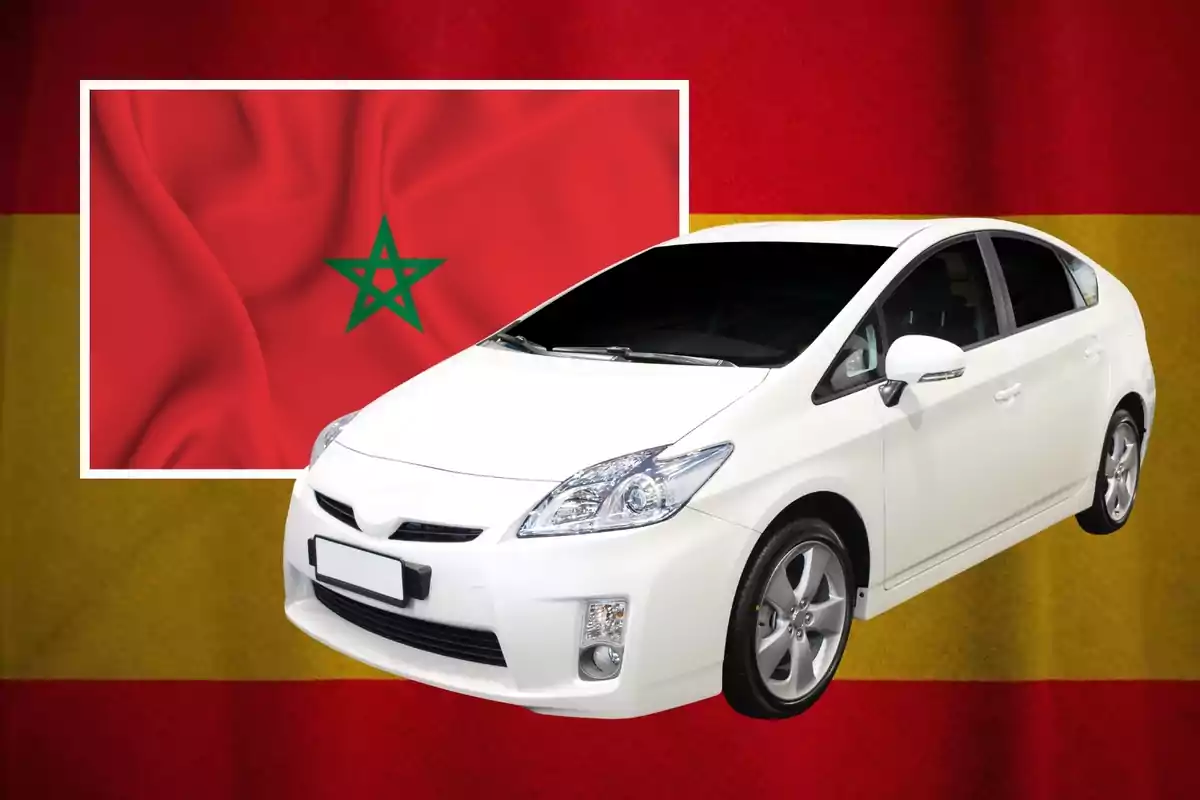 Un coche blanco frente a una bandera de España con una bandera de Marruecos en la esquina superior izquierda.