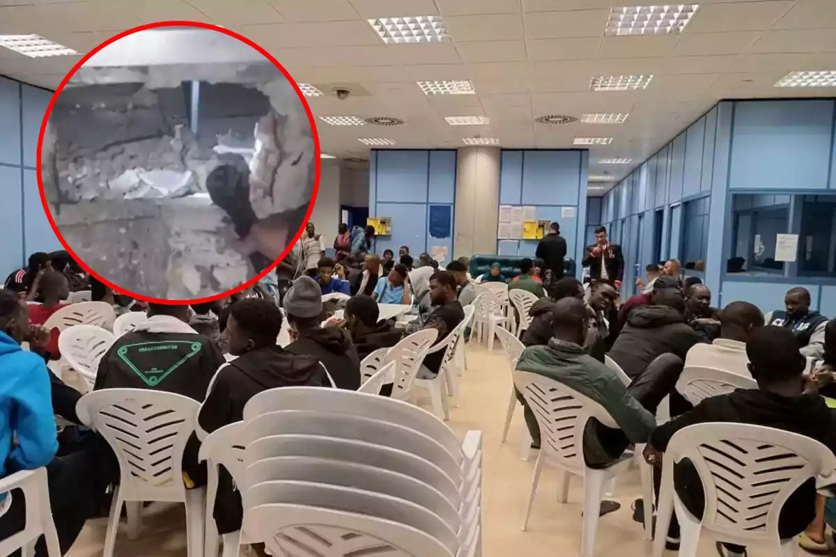 Un grupo de personas sentadas en sillas de plástico en una sala amplia con techo de paneles y paredes de vidrio, con un recuadro que muestra un agujero en una pared.