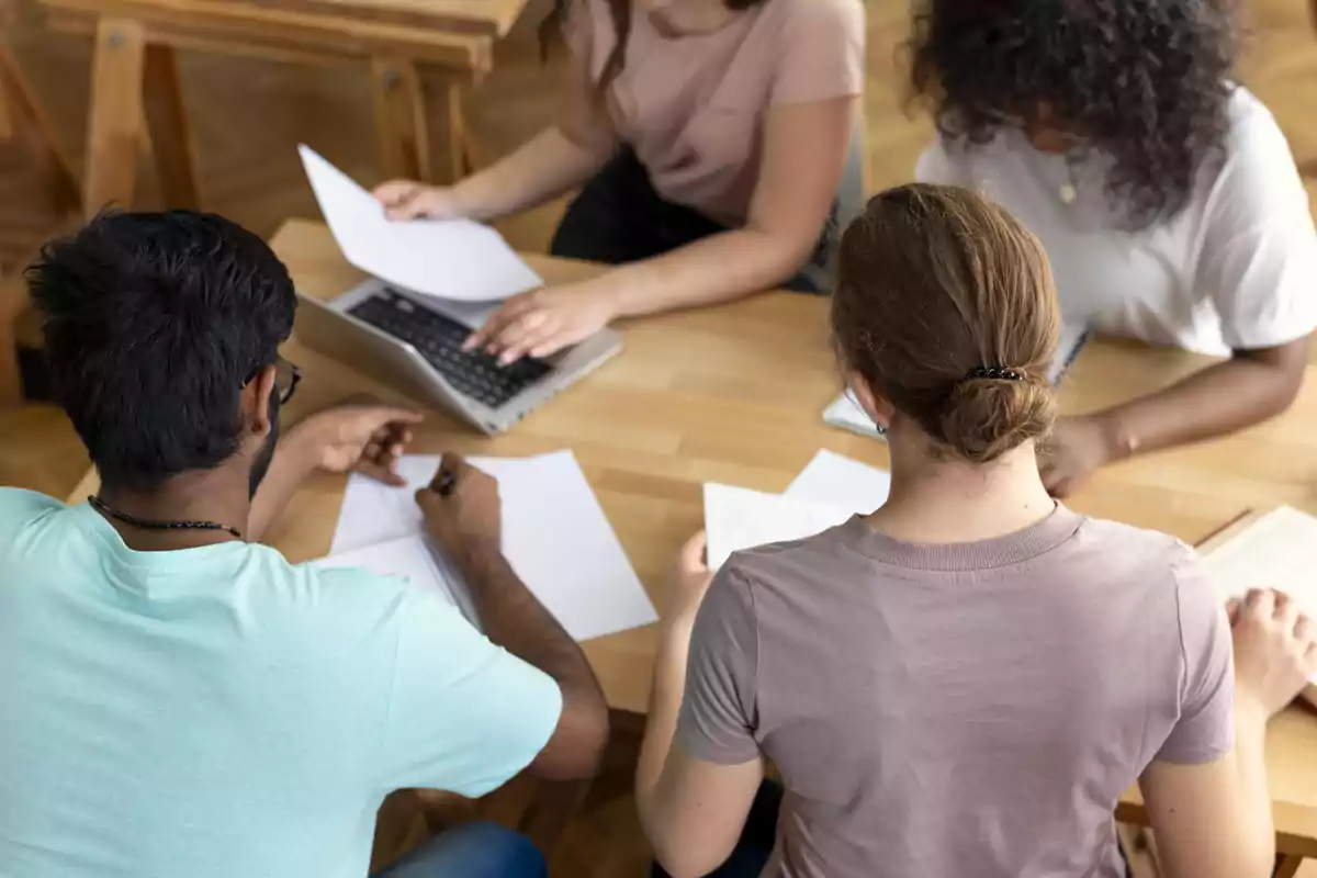 Un grupo de personas trabajando en una mesa con documentos y una computadora portátil.