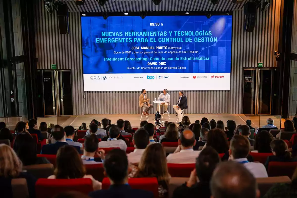 Una conferencia sobre nuevas herramientas y tecnologías emergentes para el control de gestión con tres personas en el escenario y una audiencia sentada frente a ellos.