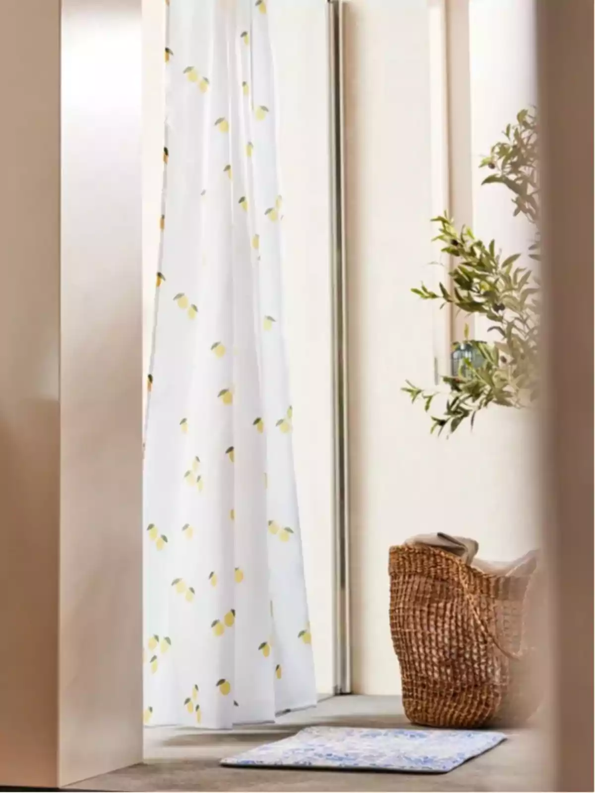 Cortina de baño con estampado de limones junto a una planta y una cesta de mimbre. Cortina de baño con estampado de limones junto a una planta y una cesta de mimbre.