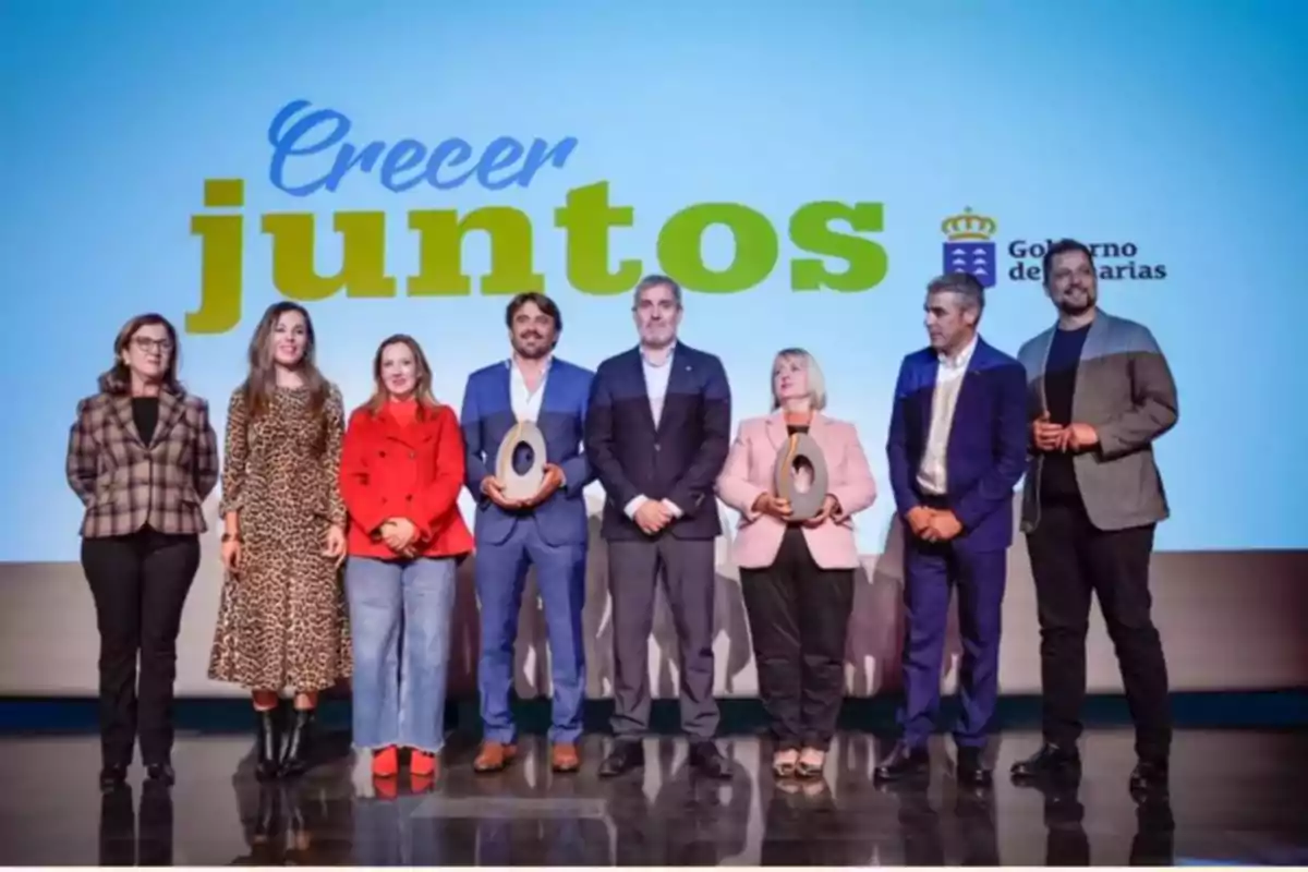 Un grupo de personas posando en un escenario con el texto "Crecer juntos" y el logo del Gobierno de Canarias al fondo.