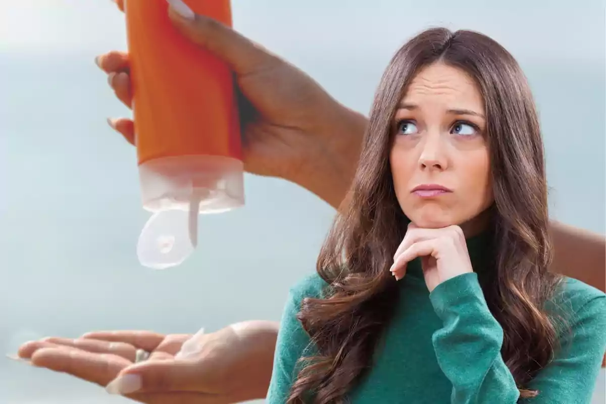 Mujer pensativa con suéter verde mirando hacia arriba mientras una mano vierte loción de una botella naranja en la palma de otra mano.