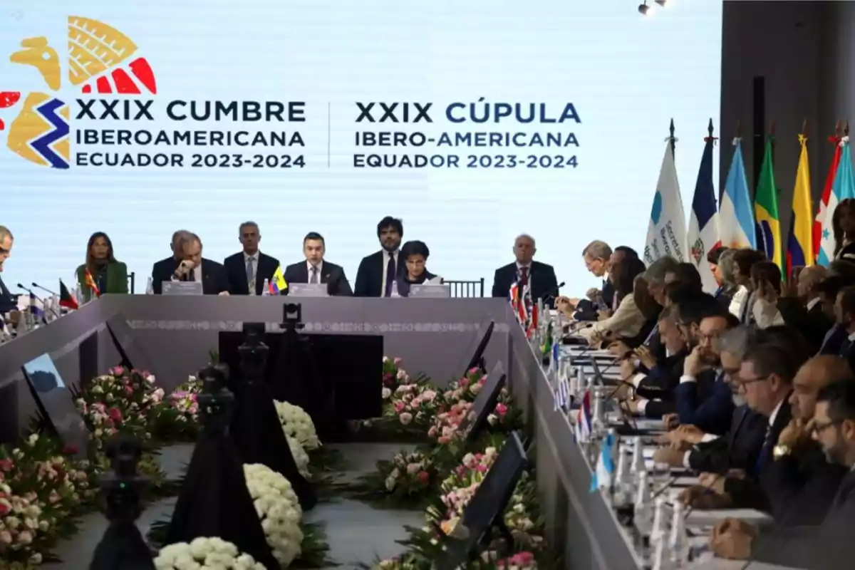 Reunión de líderes en la XXIX Cumbre Iberoamericana en Ecuador 2023-2024 con banderas de varios países y un escenario decorado con flores.