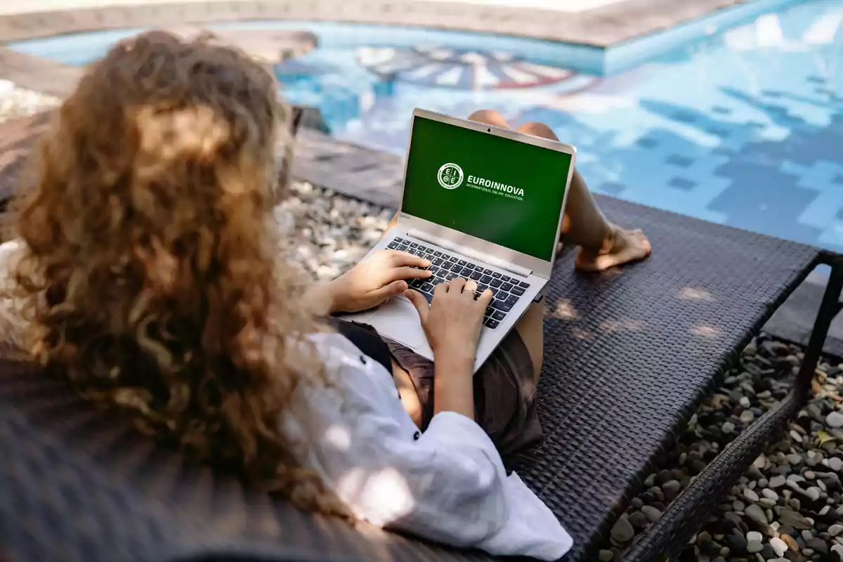 Persona usando una laptop junto a una piscina.