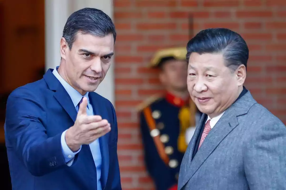 Dos hombres de traje conversando mientras uno de ellos hace un gesto con la mano.