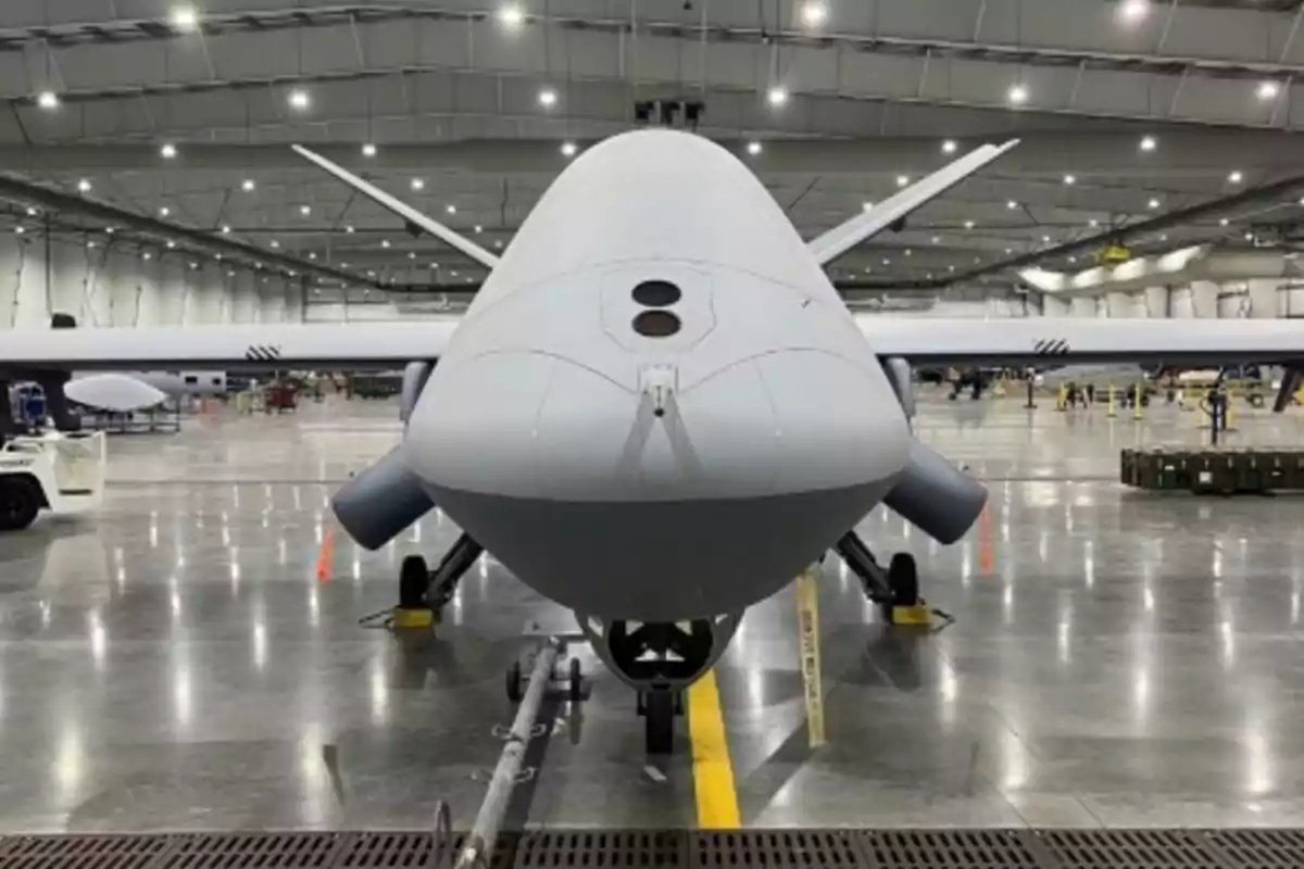 Un dron grande estacionado en el interior de un hangar iluminado.