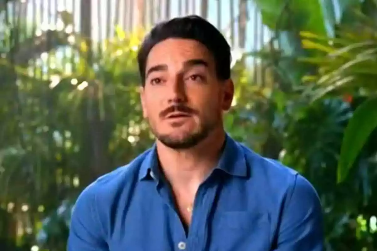 Damián Quintero con barba y camisa azul está hablando frente a un fondo de vegetación en Supervivientes. Damián Quintero con barba y camisa azul está hablando frente a un fondo de vegetación en Supervivientes.