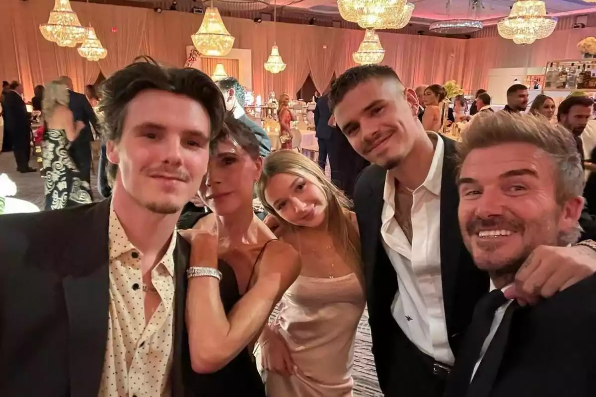 A group of people posing for a selfie at a fancy event with chandeliers in the background. A group of people posing for a selfie at a fancy event with chandeliers in the background.