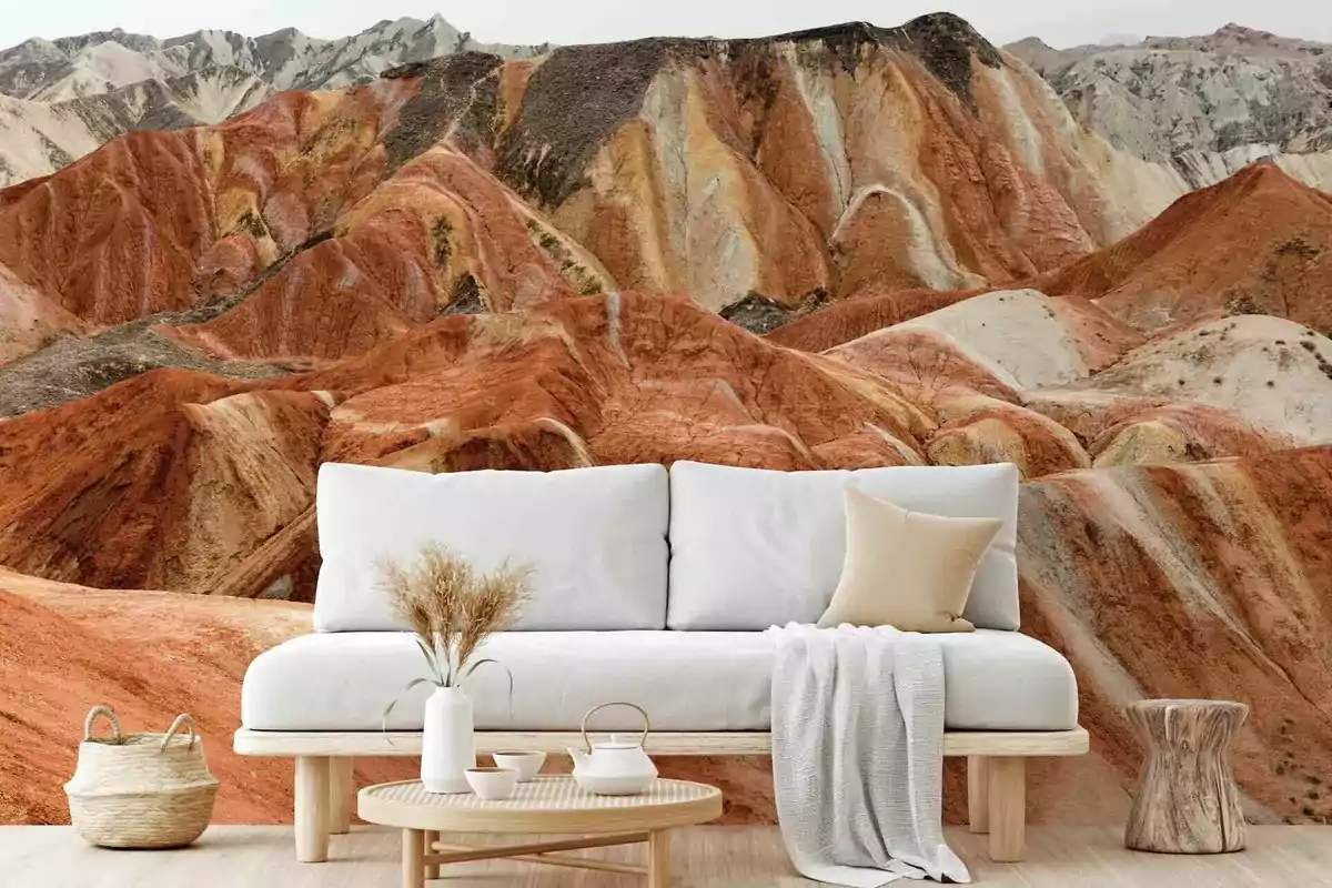 Sala de estar con sofá blanco y decoración minimalista frente a un mural de montañas coloridas.