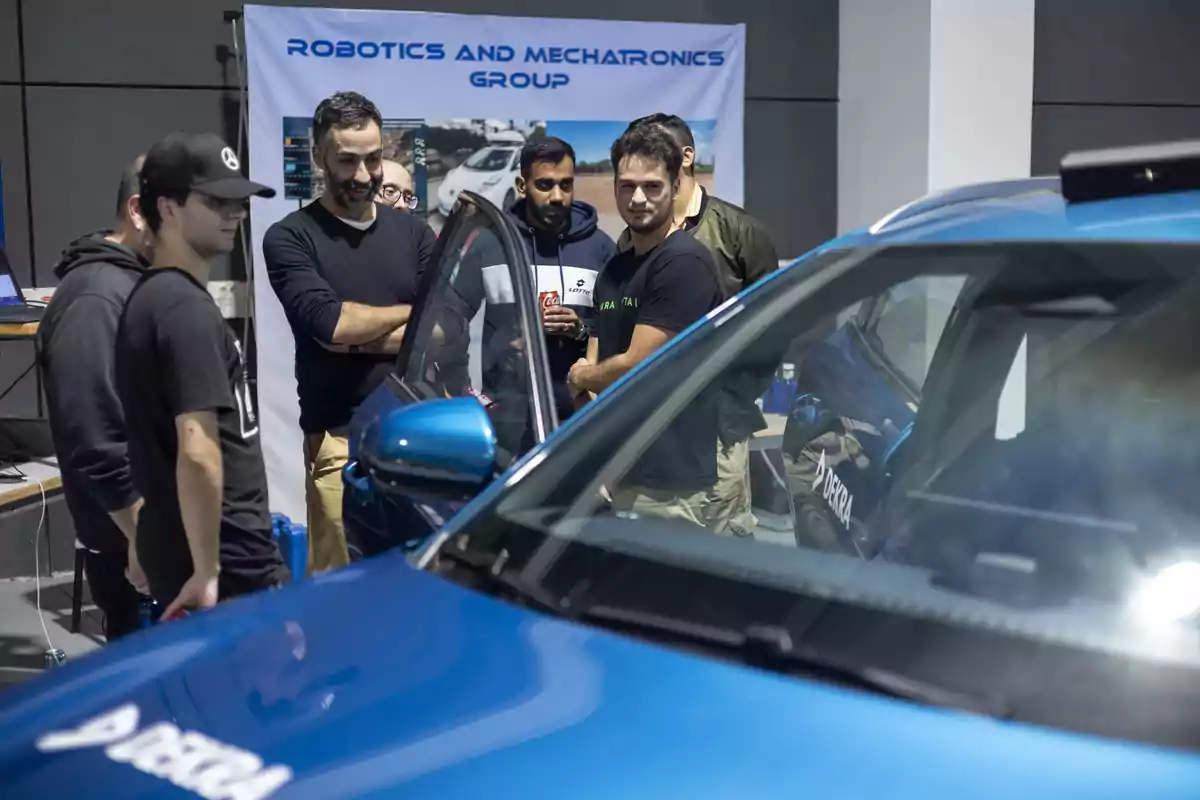 Un grupo de personas observa un automóvil azul en una exhibición de robótica y mecatrónica.